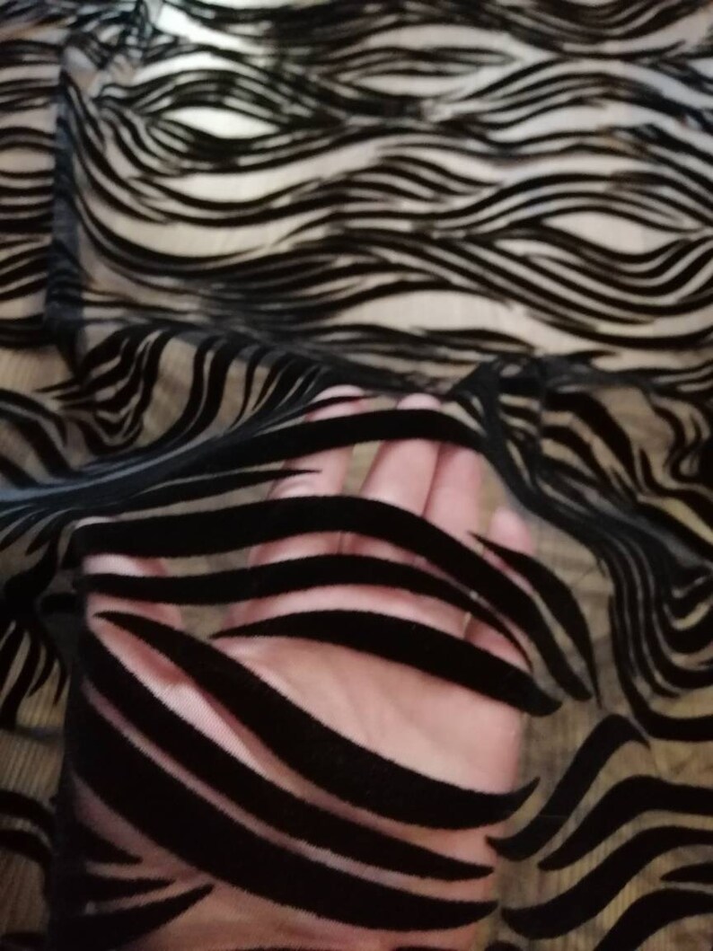 May include: Black sheer fabric with a wavy, striped pattern. The fabric is translucent and the stripes are made of a velvet-like material.