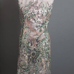 May include: A sheer fabric with a green, gold, and pink sequined design. The fabric is draped over a dress form.