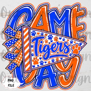 May include: A digital graphic design featuring the text GAME DAY in bold blue and orange letters. A triangular pennant is centred, displaying the word Tigers in blue script, surrounded by small blue and orange paw prints and hearts.