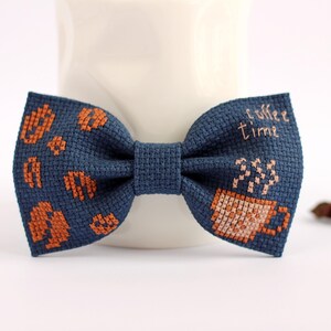 May include: A blue bow tie with a coffee cup and the text "coffee time" embroidered in orange thread.