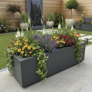 May include: A dark grey rectangular planter filled with vibrant flowers and trailing greenery. The flowers are a mix of yellow, red, white, and purple. The planter is in a garden setting, with a water feature and wooden fence visible in the background.