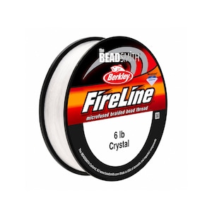 May include: A spool of white Berkley FireLine microfused braided bead thread by The Beadsmith. The label features red, orange, and black graphics with the text 6 lb Crystal. The spool is round with a black plastic edge and clear white thread.