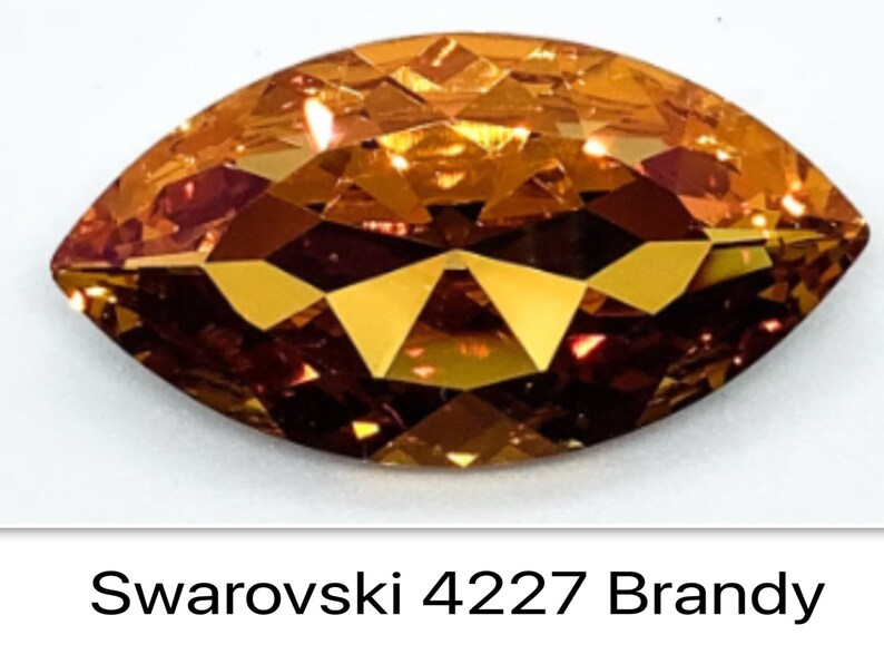 Peut inclure: Gros plan sur un seul cristal Swarovski de forme marquise, facett&eacute;, de couleur ambre. Le cristal est &eacute;tiquet&eacute; "Swarovski 4227 Brandy".