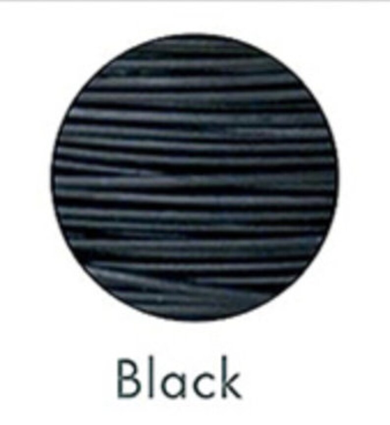 May include: A black, round object with horizontal lines, set against a white background. The word "Black" is written in a simple, sans-serif font below the object. The object appears to be a sample of a material or product.