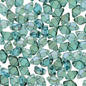 May include: A collection of teal-colored, irregular-shaped beads with a diagonal striped pattern. The beads have a translucent quality, with variations in color and shape. These beads are suitable for jewelry making and crafting projects.