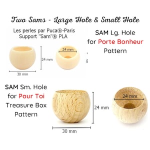 May include: Two wooden beads with different sized holes. The larger bead has a 24 mm diameter and a 30 mm circumference. The smaller bead has a 24 mm diameter and a 30 mm circumference. The beads are labeled "SAM Lg. Hole for Porte Bonheur Pattern" and "SAM Sm. Hole for Pour Toi Treasure Box Pattern".