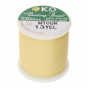 Pode incluir: Um carretel de fio de miçangas amarelo. O rótulo diz "K.O. Beading Thread" com detalhes incluindo "330dtex", "100% NYLON" e "Made in Japan". O carretel é rotulado "13 YEL" e "MTOOR".