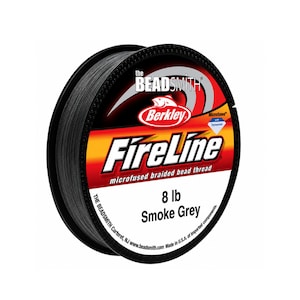 Peut inclure: Une bobine de fil de perlage tressé microfusionné FireLine noir de The Beadsmith. L'étiquette affiche le logo Berkley, le texte 8 lb Smoke Grey, et indique qu'il est microfusionné avec du Dyneema. La bobine est noire avec un design circulaire.