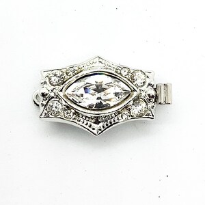 May include: Silver-toned clasp with a clear marquise-shaped crystal surrounded by smaller clear crystals.