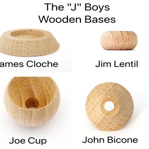 Könnte beinhalten: Vier Holzsockel für ein Spiel, jeder mit einer anderen Form: eine flache Scheibe, ein Ring, eine Tasse und ein Kegel. Die Sockel sind aus hellbraunem Holz gefertigt und haben eine glatte Oberfläche.