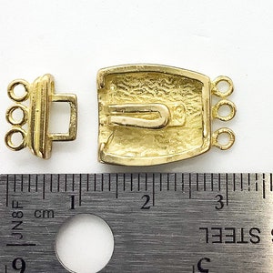 May include: Gold-toned metal clasp with a textured design and three loops on each side. The clasp measures approximately 1 inch in length.