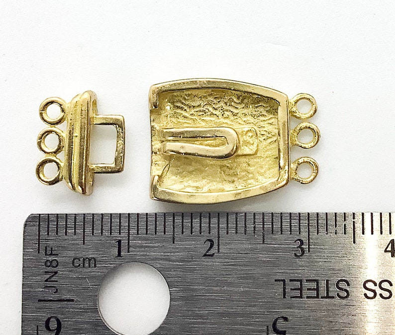 May include: Gold-toned metal clasp with a textured design and three loops on each side. The clasp measures approximately 1 inch in length.