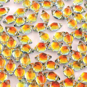 May include: A collection of faceted glass beads with a mix of yellow, orange, and clear colors. The beads have a diamond or teardrop shape, with a shiny, reflective surface. These beads are suitable for jewelry making and craft projects.