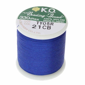 Pode incluir: Um carretel de fio de miçangas K.O. em azul vibrante. O rótulo indica que é 100% nylon, 330dtex e fabricado no Japão. O carretel é branco com texto verde e dourado.