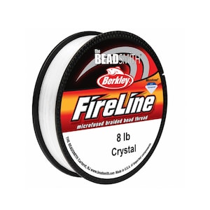 May include: A spool of white FireLine microfused braided bead thread by The Beadsmith. The label features the Berkley logo, the text 8 lb Crystal, and indicates it is microfused with Dyneema. The spool has a black rim and white thread.