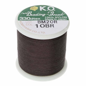May include: A spool of K.O. Beading Thread, 100% nylon, in a dark brown colour. The label includes the text "BM20R 1 OBR" and "Made in Japan". The spool is on a white base.