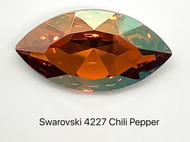 Peut inclure: Un seul cristal Swarovski en forme de larme, facett&eacute;, rouge orang&eacute; avec un reflet iridescent vert. Le cristal est &eacute;tiquet&eacute; "Swarovski 4227 Chili Pepper".