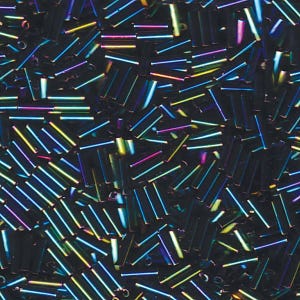 Op de afbeelding: Close-up van een verzameling iriserende, cilindrische kralen. De kralen zijn voornamelijk donker met een glinsterend, veelkleurig effect, dat tinten blauw, groen, geel en roze weerspiegelt. De kralen zijn verspreid, wat suggereert dat ze los zijn en klaar voor gebruik in sieraden of knutselwerk.