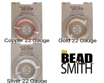 May include: Three spools of wire for jewelry making. The spools are labeled "Copper 22 Gauge", "Gold 22 Gauge", and "Silver 22 Gauge". The wire is a medium temper and semi-flexible. The spools are packaged with a white background and gold floral design.