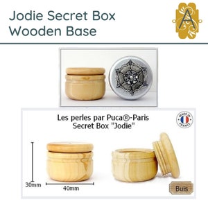 May include: A wooden secret box with a lid, labelled "Jodie Secret Box Wooden Base". The box is 10 cm in diameter and 7.5 cm tall. The box is made of wood and has a natural wood finish. The box is made in France.