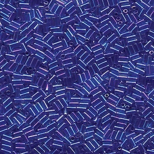 May include: Close-up of a pile of small, rectangular, dark blue beads. The beads have a slight iridescent sheen, with hints of purple and pink. These beads are likely used for jewelry making or other craft projects.