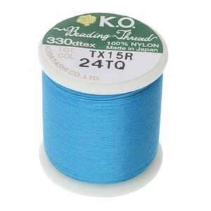 Pode incluir: Um carretel de fio para miçangas K.O. em um vibrante turquesa. O rótulo indica "Beading Thread", "100% NYLON" e "Made in Japan". O texto "TX15R 24TQ" também é visível. O carretel é cilíndrico.