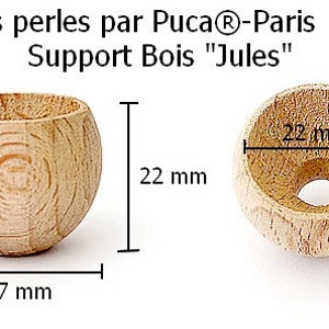 May include: A wooden bead support for jewelry making, measuring 27 mm in diameter and 22 mm in height. The support is made of natural wood and has a smooth, rounded surface. It is labeled "Les perles par Puca®-Paris Support Bois "Jules"" and "Made in France".
