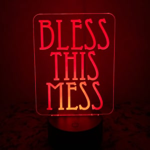 Puede incluir: Luz nocturna LED roja con un letrero de acrílico blanco que dice "Bless This Mess".
