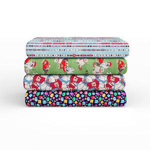 May include: Stack of four fabric panels with different patterns. The top panel is light blue with a repeating pattern of red and white beads and the text "WHAT A CATCH" and "LOVERS IN KC". The second panel is green with a repeating pattern of raccoons wearing red and white football jerseys. The third panel is white with a repeating pattern of raccoons wearing red and white football jerseys with the numbers "87" and "18". The bottom panel is dark blue with a repeating pattern of colourful gemstones.