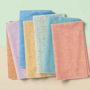 May include: A stack of six fabric squares with a speckled pattern in various pastel colors, including light blue, yellow, green, and pink.