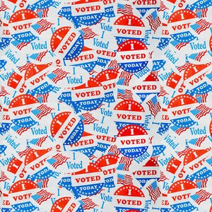 May include: A repeating pattern of red, white, and blue "I Voted" stickers. The stickers feature a star-spangled banner design and the text "I Voted" in bold, white letters.