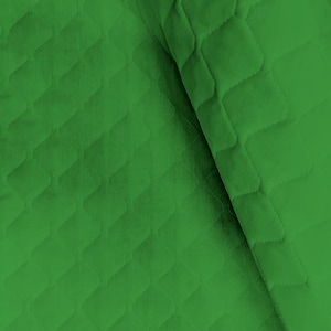 May include: Close-up of a bright green quilted fabric. The fabric has a repeating diamond pattern created by the stitching. The material is folded over, showing the texture and depth of the fabric. The color is a vibrant, solid green.