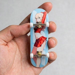 May include: A miniature skateboard with a light blue deck featuring an anime-style illustration of a woman in a red outfit. The skateboard has silver trucks and white wheels. A fun collectible item.