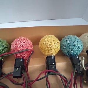 May include: A set of six vintage Christmas lights with textured bulbs in green, red, yellow, blue, and white. The lights are wired together and have a plug on the end.