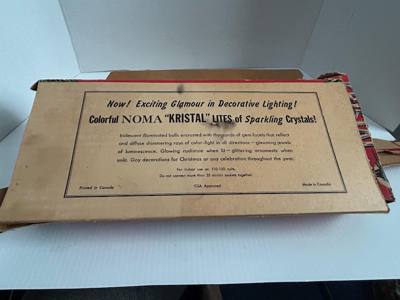 May include: A vintage box for NOMA "KRISTAL" LITES Christmas lights. The box is brown with red and white accents. The text on the box reads "Now! Exciting Glamour in Decorative Lighting! Colorful NOMA "KRISTAL" LITES of Sparkling Crystals!"  The box is printed in Canada and is CSA Approved.