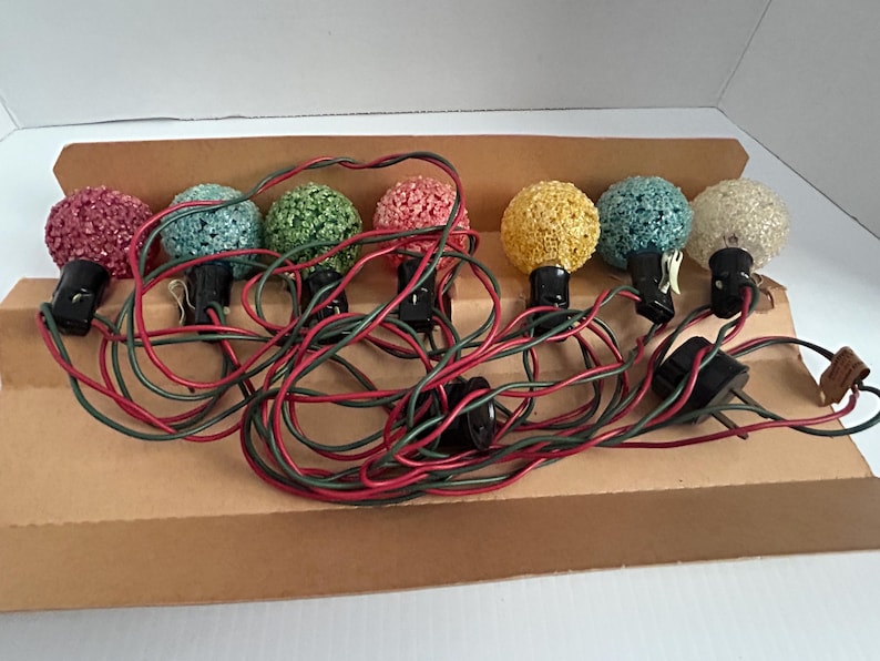 May include: A set of eight vintage Christmas lights with colorful, textured bulbs. The lights are wired with red and green wires and are packaged in a brown cardboard box.