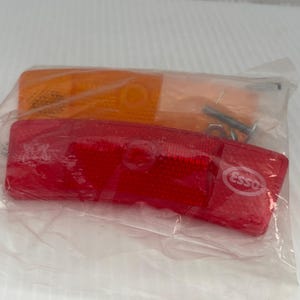Peut inclure: Deux feux de position automobiles, un orange et un rouge, emballés dans un sac en plastique transparent. Le feu rouge porte le logo "Esso". Comprend le matériel de montage.