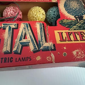May include: Vintage box of Christmas lights with the words "Crystal Lites Electric Lamps" on the front. The box features a red background with a white border and a variety of colorful lights.