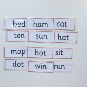 May include: White cards with black text, each card has a different word on it. The words are: bed, ham, cat, ten, sun, hat, mop, hot, sit, dot, win, run.