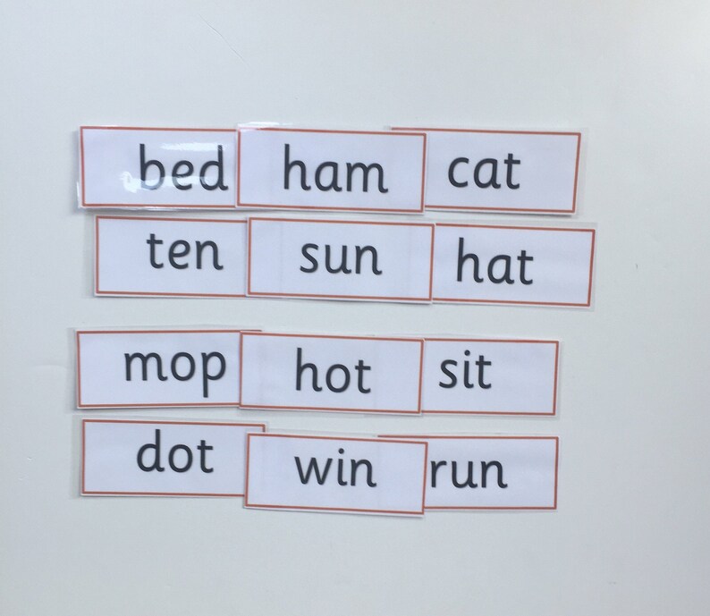 May include: White cards with black text, each card has a different word on it. The words are: bed, ham, cat, ten, sun, hat, mop, hot, sit, dot, win, run.