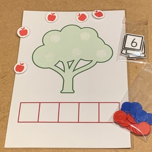 May include: A green tree with six red apples on it. There are six empty squares below the tree. A bag of red and blue counters is on the right side of the image. A number six is visible in a bag on the top right of the image.