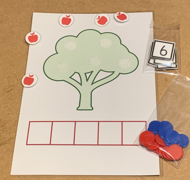 May include: A green tree with six red apples on it. There are six empty squares below the tree. A bag of red and blue counters is on the right side of the image. A number six is visible in a bag on the top right of the image.