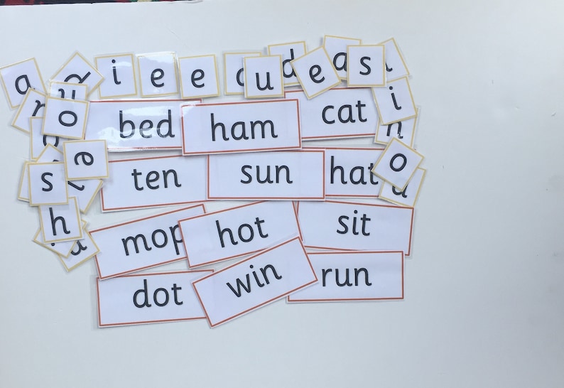May include: A set of white flashcards with black text, featuring common sight words for early readers. The words include "bed", "ham", "ten", "sun", "mop", "hot", "dot", "win", "cat", "hat", "sit", "run".