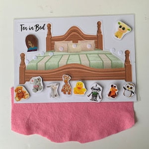 May include: A felt play set with a wooden bed and various animal and toy characters. The set includes a sheep, a giraffe, a duck, a robot, a bear, a donkey, an elephant, an owl, and a dog. The set is titled "Ten in Bed".