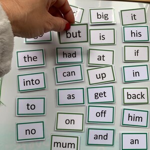 May include: A set of 24 magnetic word tiles with green borders and white backgrounds. The words include "big", "it", "but", "is", "his", "the", "had", "if", "at", "can", "up", "in", "into", "as", "get", "back", "to", "off", "on", "him", "no", "and", "mum", "an", "a", "of", "not", and "got".