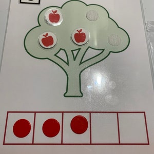 May include: A green tree with three red apples on it. The number 3 is written on a white square. There are three red circles in a row of five squares.