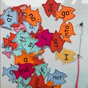 May include: A collection of colourful fish-shaped cards with words written on them, including "at", "no", "big", "go", "ff", "is", "me", "but", "if", "you", "im", "x", "not", "I", "get", "into".