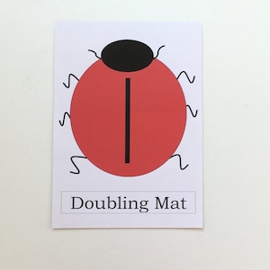 May include: A red ladybug with black spots and a black line down the middle. The text "Doubling Mat" is printed below the ladybug.