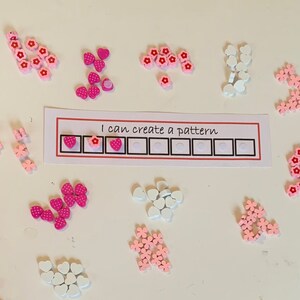 May include: A pink and white heart and flower pattern activity for children. The card says "I can create a pattern".