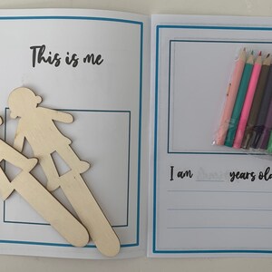 May include: A blank book with a blue border and the text "This is me" on the front cover. The book has a page with a blank space for drawing and the text "I am ____ years old". The book comes with two wooden cutout figures and a pack of coloured pencils.